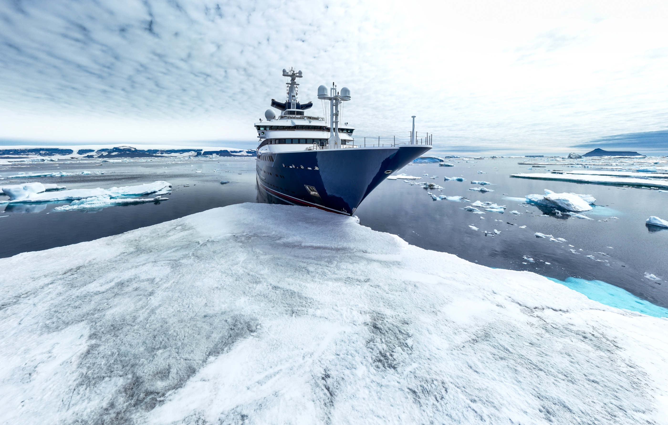 Explorer yacht resting against an ice floe, Antarctic Peninsula