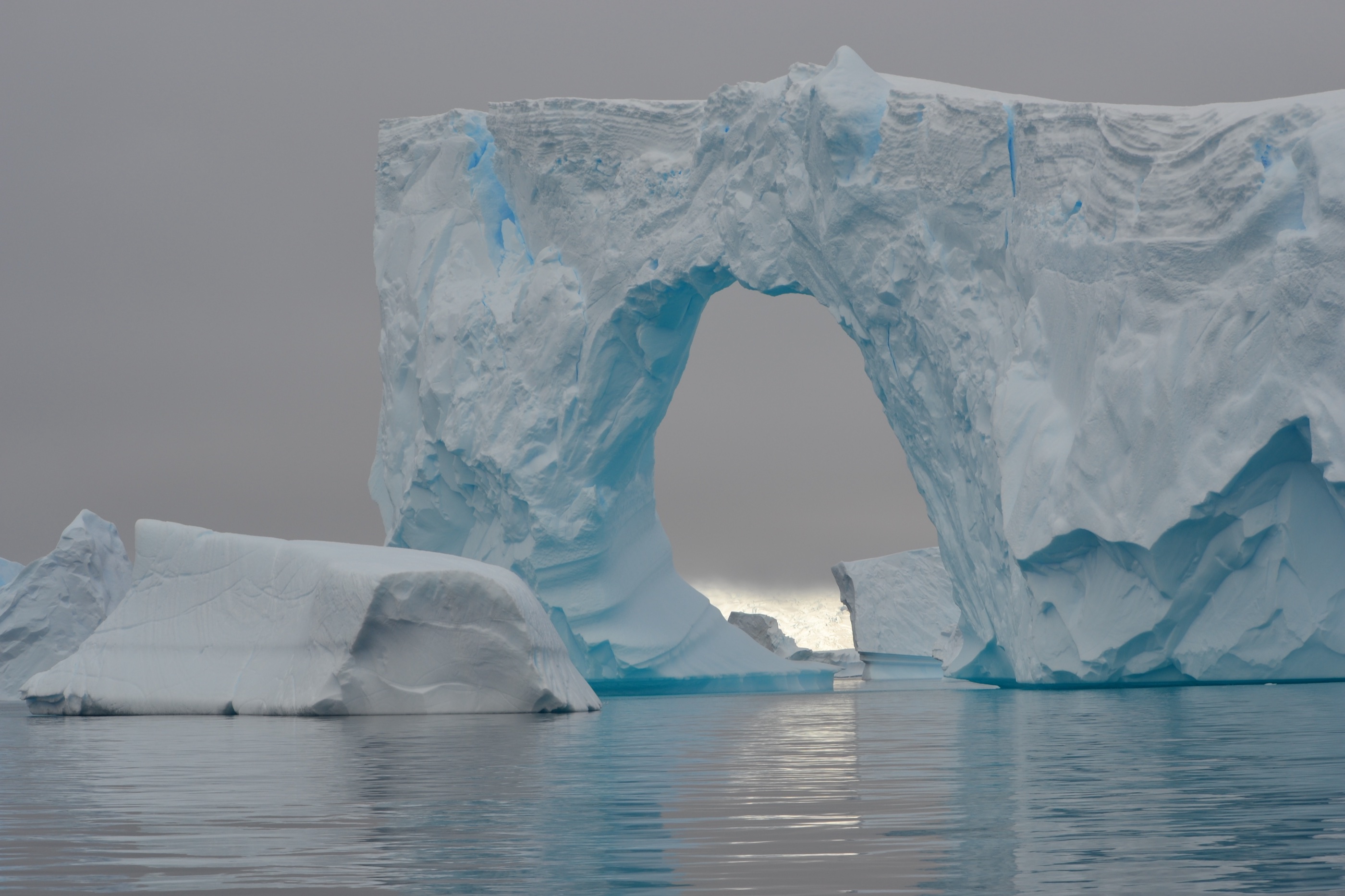 Sculpted iceberg arch in calm Antarctic water