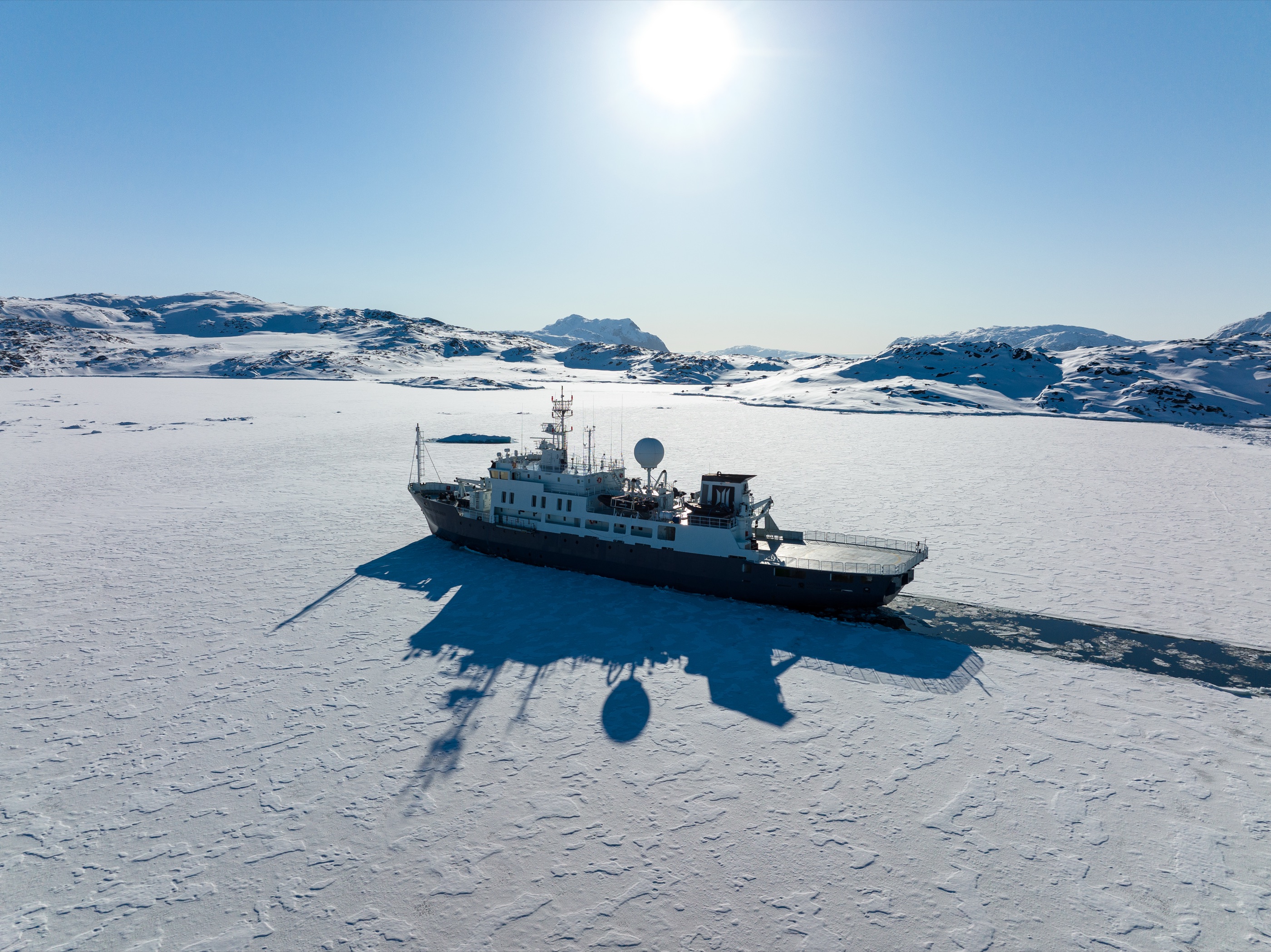 Explorer yacht parked at the fast-ice edge in low sun