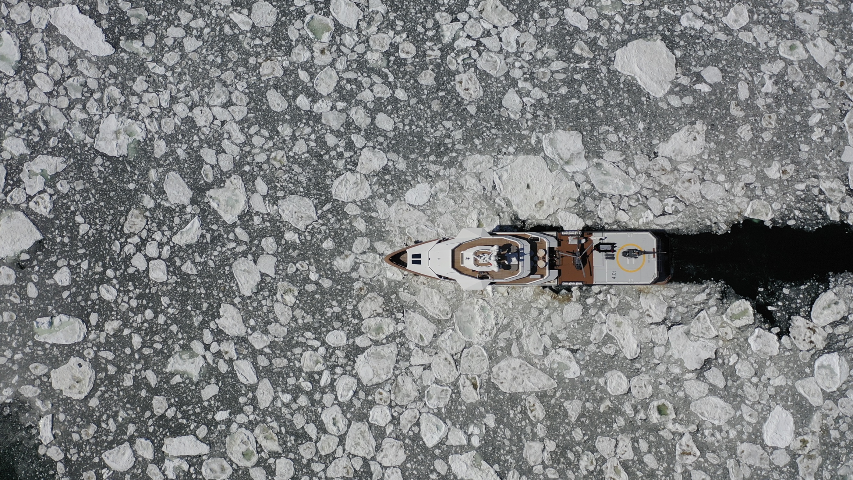 Explorer yacht cutting a channel through brash ice, seen from above